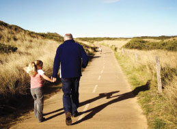Grandfather and granddaughter walking down a road